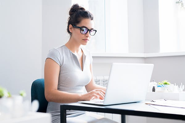 Portrait-of-beautiful-young-woman-wearing-glasses-using-laptop-sitting-at-table-in-cafe